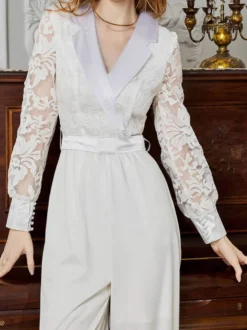 Combinaison blanche à manches longues en dentelle taille haute et jambes larges style nuptial.