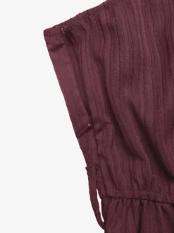 Combinaison-short d'été décontractée pour femme mauve asymétrique avec ceinture et tissu texturé à nouer à la taille.
