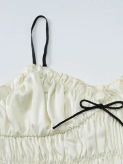 Ensemble deux pièces abricot chic plissé idéal pour les vacances avec bretelles et col à volants jupe sans manches à volants.