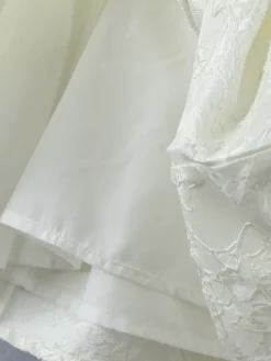 Robe blanche chic à nœuds sculptants et sans manches col carré idéale pour une soirée romantique.