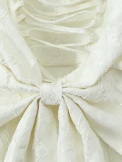 Robe blanche chic à nœuds sculptants et sans manches col carré idéale pour une soirée romantique.