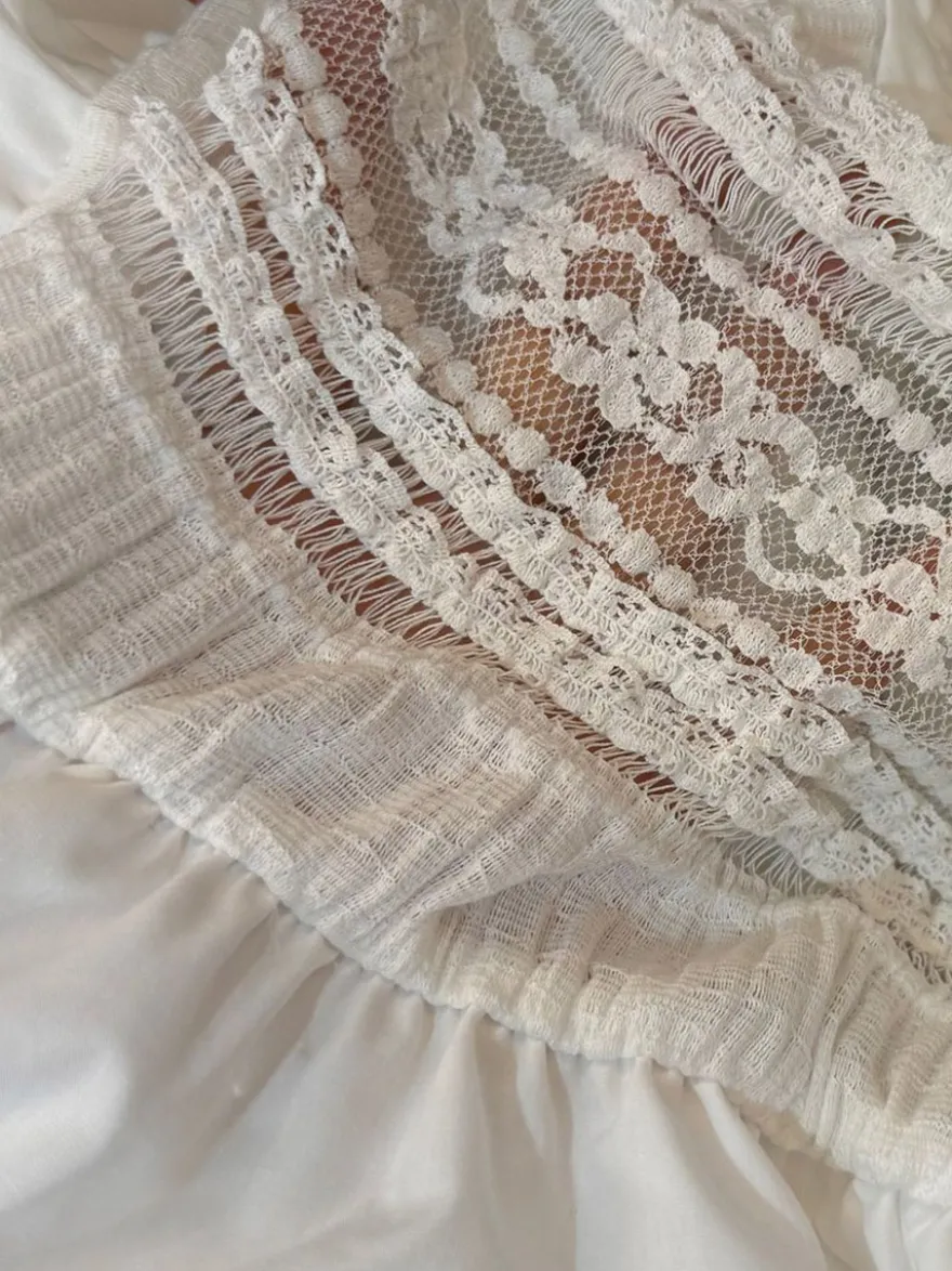 Robe bohème courte trapèze à bretelles fines et dentelle ajourée taille haute et bustier noué.