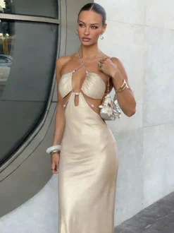 Robe de soirée abricot en satin sirène moulante à strass dos nu fente latérale et décolleté dos nu ornée de strass.