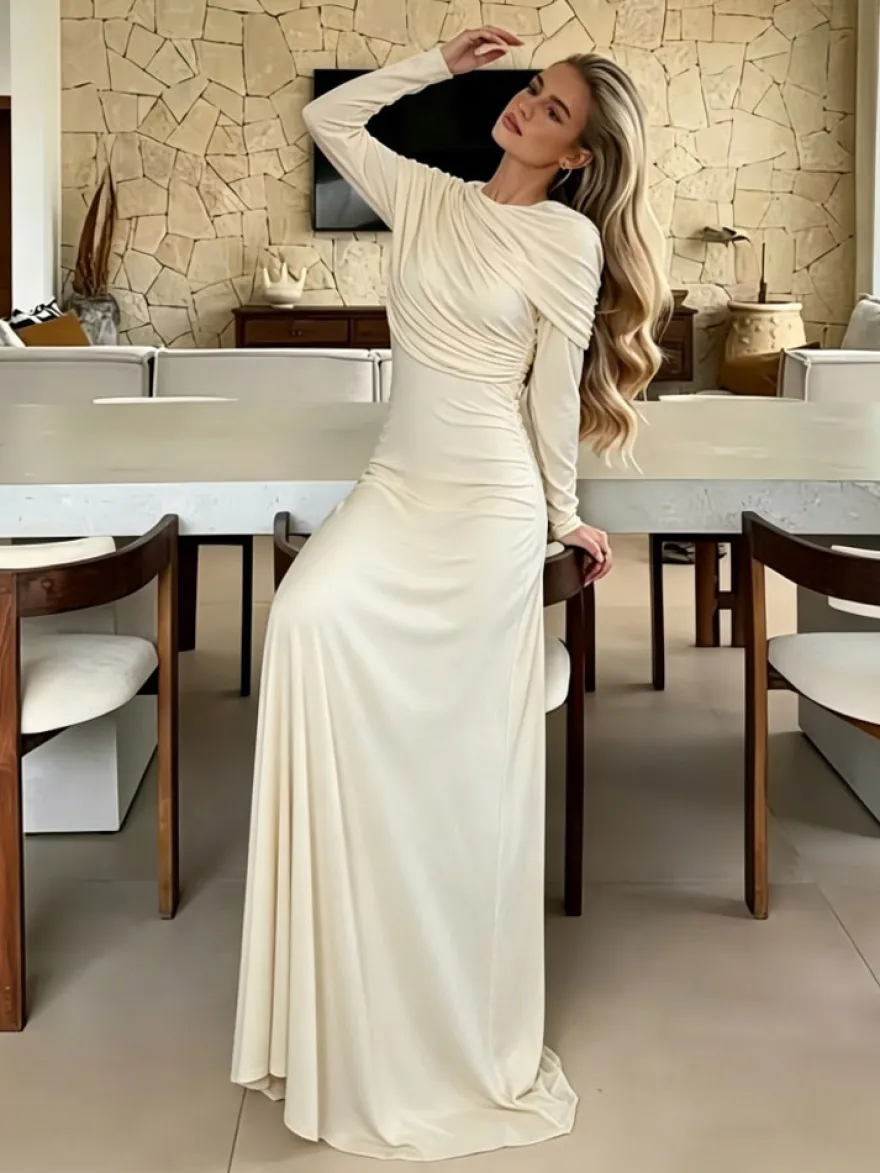 Robe de soirée élégante et moulante couleur crème épaules drapées et manches longues.