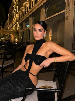 Robe de soirée longue moulante à paillettes col montant et découpes sans manches et taille ajourée.